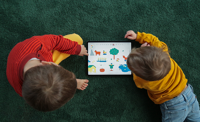 Two kids playing together on one iPad.