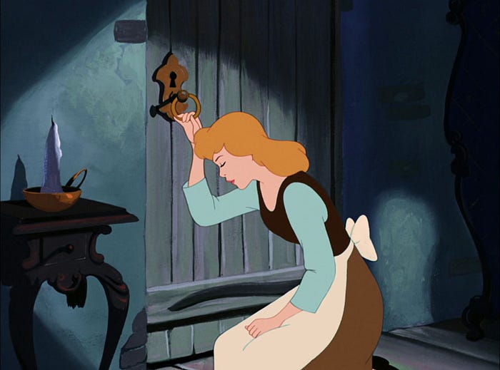 A sad blonde girl (Cinderella) in the clothing of a maid is sitting down by the locked door and holding on to the door knob. The door is locked.