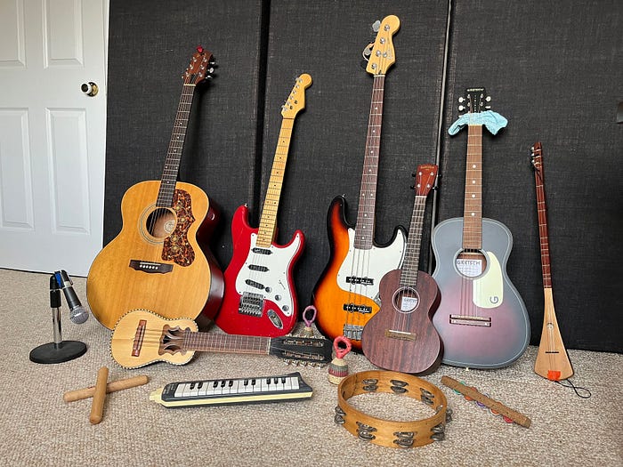 A collection of musical instruments including 4 guitars, a tambourine, a ukulele, various shakers from Africa and more.