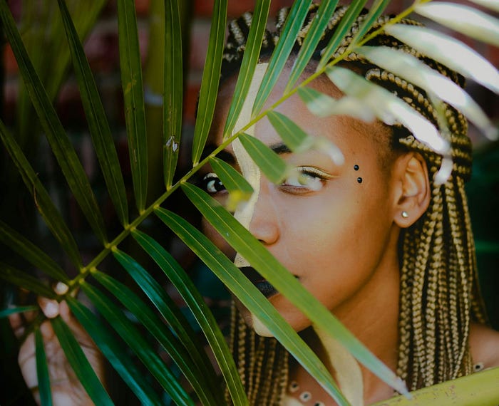 a woman holding a green leaf reflecting the cultural aspect of African-american cultural poetry