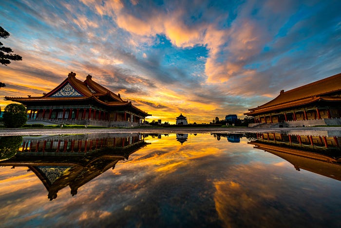 two shrines on either side of a body of water during a sunset