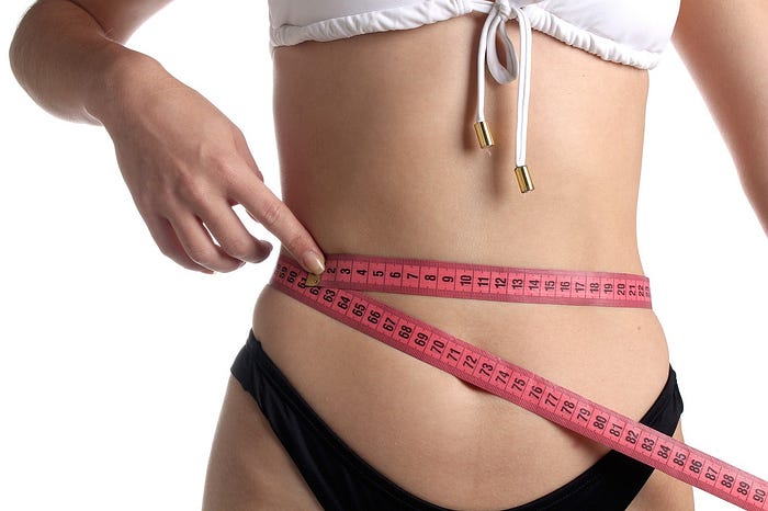 s. pic of a slim lady measuring her slim waist