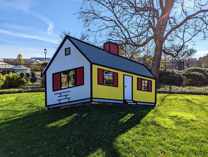 Sculpture of a house on a grassy lawn