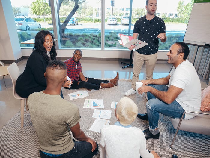 Diverse group of people sitting together discussing what appears to be business papers 