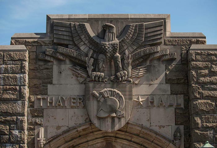A photo of the main entrance into West Point’s Thayer Hall with the Academy Crest and “Duty, Honor, Country” carved into the stone wall.