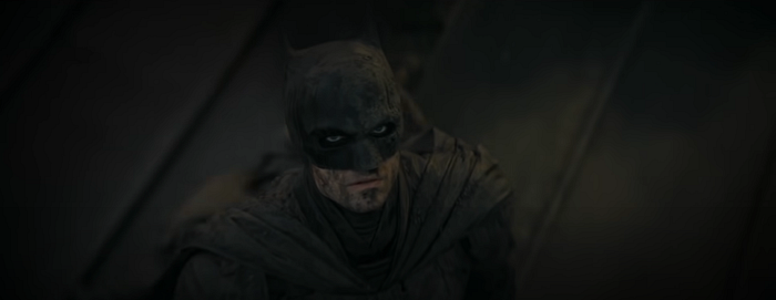 Potongan dari film Batman, Robert Pattison sebagai Batman melihat ke atas langit dengan tatapan menakutkan setelah menolong orang-orang dari banjir