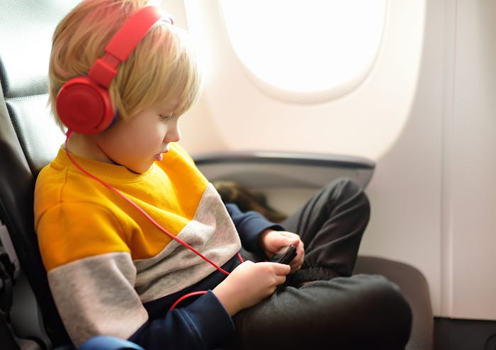 A child listening to music on an airplane.