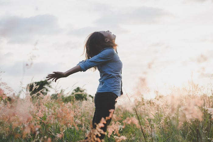 A woman in a field of flowers feeling free to illustrate spiritual freedom