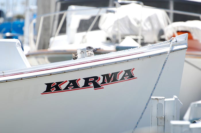 Image by TootSweetCarole on pixabay of docked boat named Karma