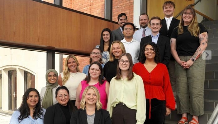 A group shot of students on a staircase dressed in business professional clothes