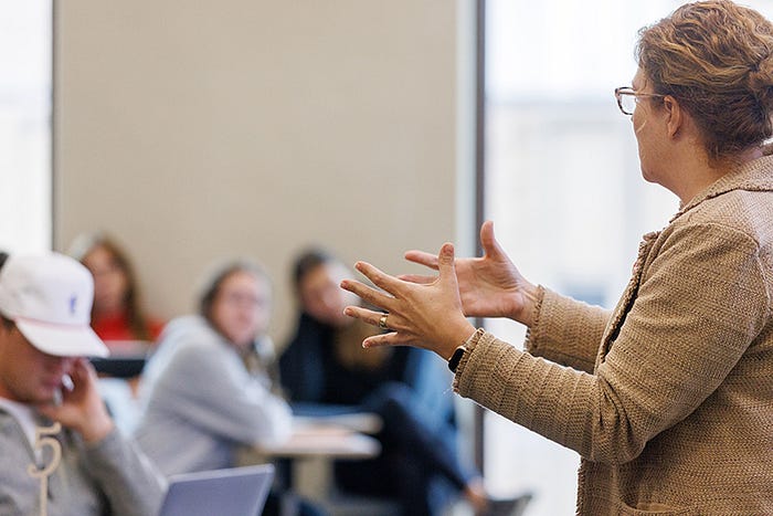 Charlotte Tritch gestures while teaching to a classroom of students.