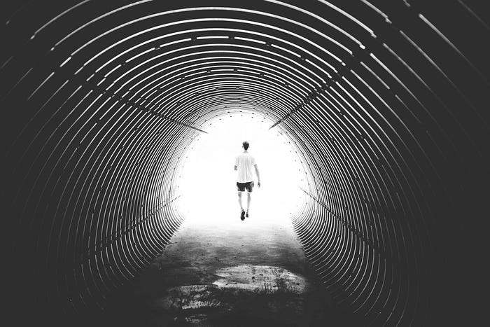 Someone walks out of a fear tunnel and out the other side.