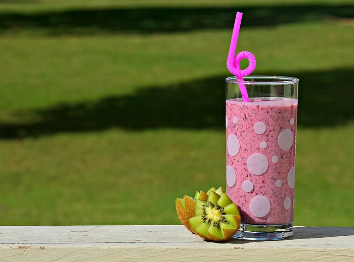A delicious pink smoothie with a purple straw