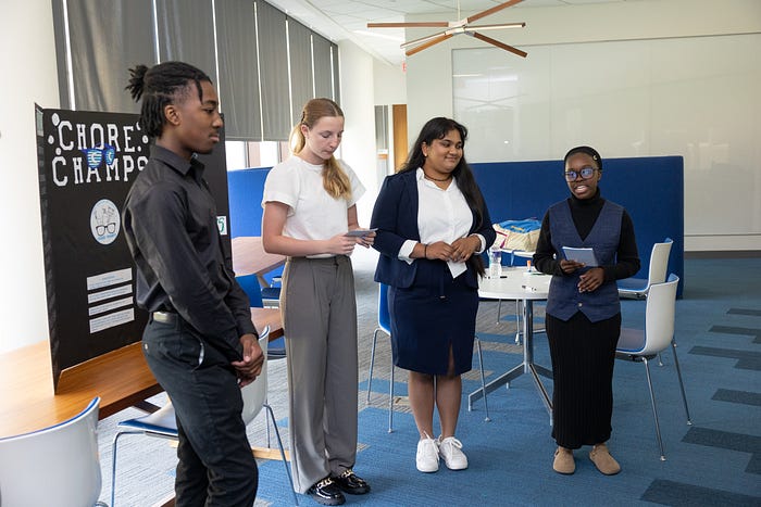 Students dressed in business clothes present their poster.