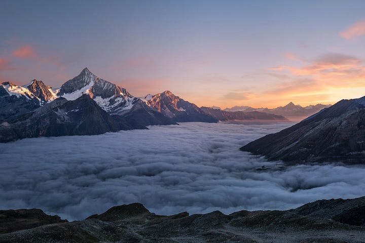 A person looking out over a vast, misty mountain range at sunrise, symbolizing the vastness of what we don't know.