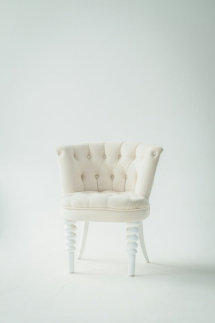 A simple, empty wooden chair placed in a sunlit room, facing a window.
