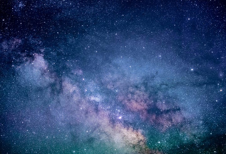 A vast, starry night sky over a silhouette of mountains, evoking a sense of wonder and scale.
