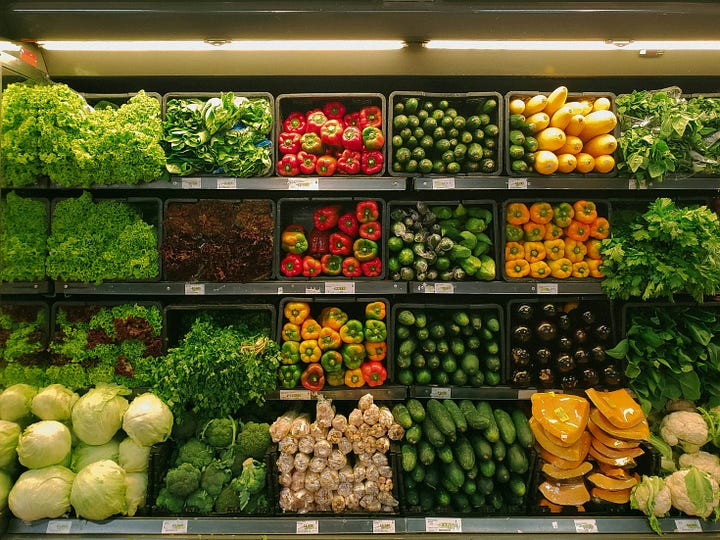 A person stands in a brightly lit supermarket aisle, looking overwhelmed by the vast number of products on the shelves.