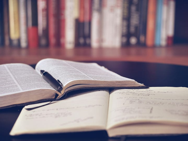 An old, leather-bound book open on a desk, with a magnifying glass resting on the page.