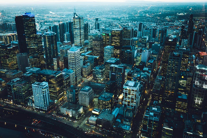 An aerial view of a sprawling city at dusk, with countless lights forming an intricate, interconnected web, symbolizing societal complexity.