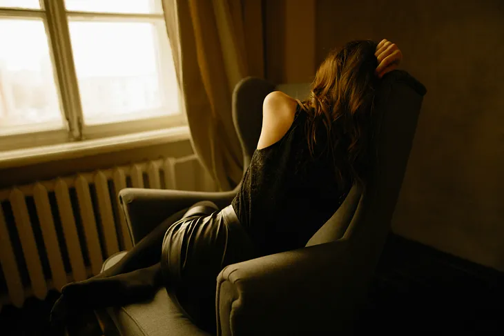 woman in trying to sleep in an arm chair. the entire photo’s in shadowy sepia tones.