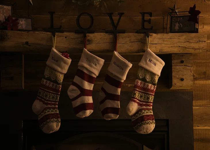 Christmas stockings in subdued colors. Above the rustic fireplace are black letters that spell LOVE.