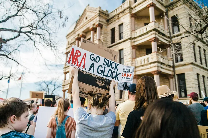 Gun protest — woman holding a sign saying NRA Go Suck A Glock