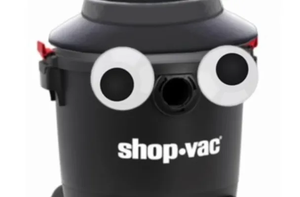 a shop vaccuum with giant googly eyes and a hat on it.