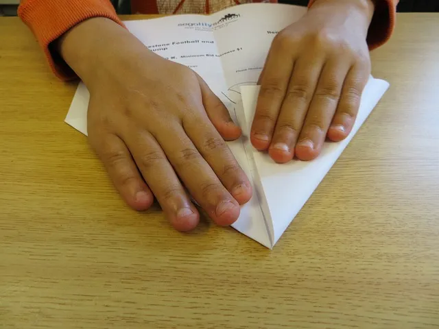 Child’s hands making a paper aeroplane.