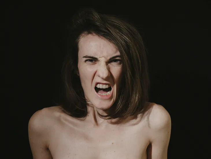 an angry topless woman with black background