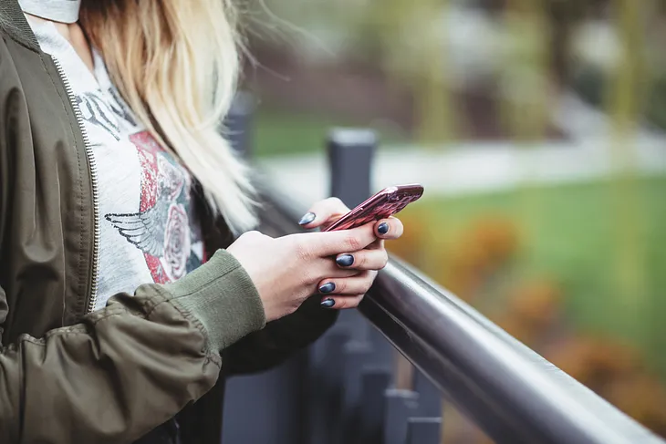 Woman holds her phone and types.