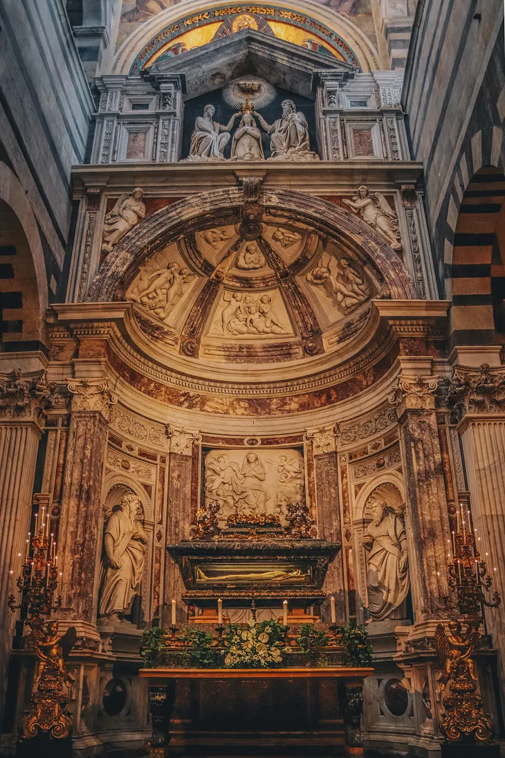 Antique classical tomb inside a domed ornate church.