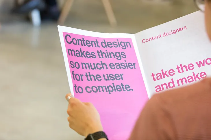 A woman reading a page that says “Content design makes it so much easier for the user to complete.”