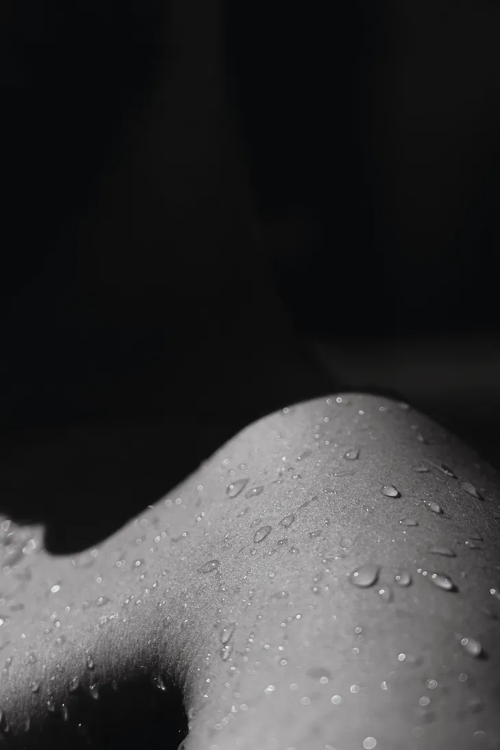 Black and white image of beads of water on a shoulder