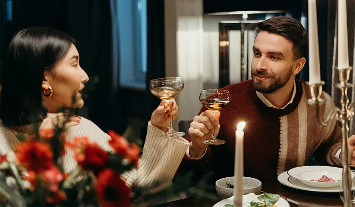 A couple toasting each other in a candlelit dinner