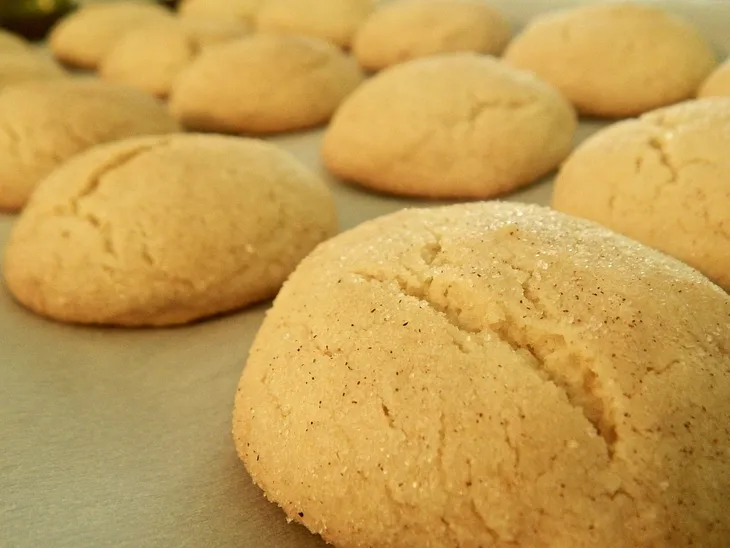 A baking sheet of puffy, freshly baked cinnamon-sugar dusted cookies