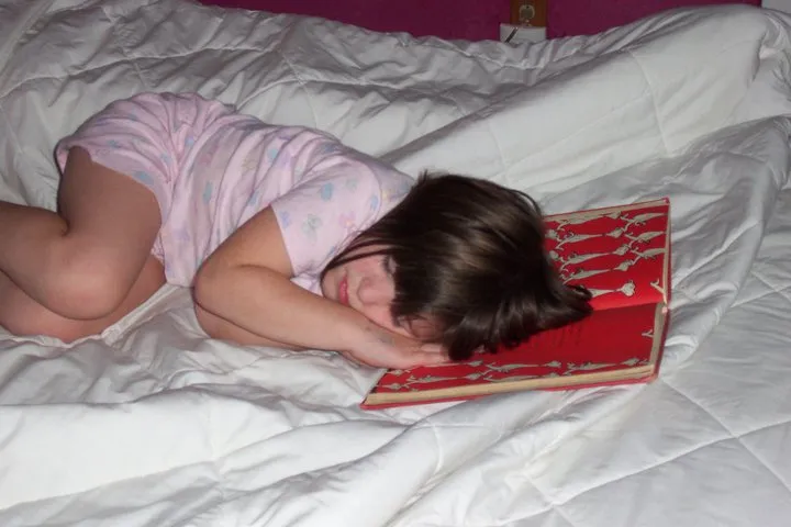 little white girl (author’s daughter) with brown hair asleep in bed with her head resting on an open Dr. Seuss book