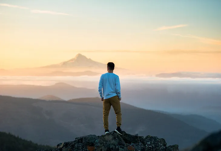 Person standing on top of a mountain looking out over the range