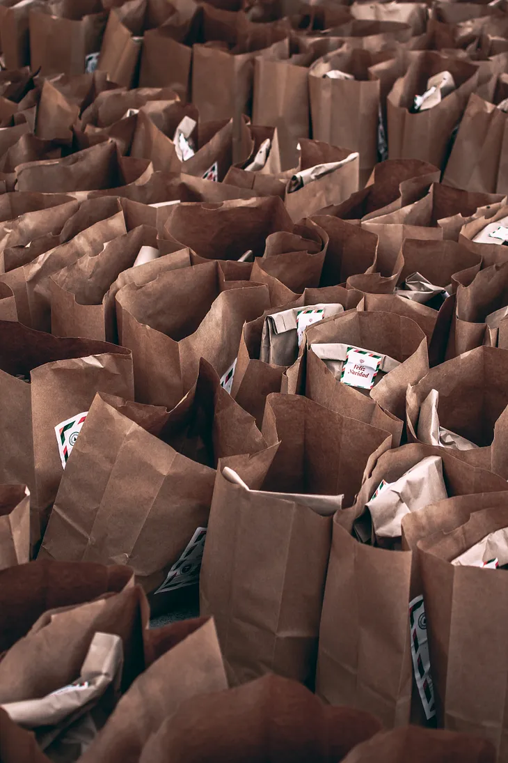 A photo of many brown grocery sacks filled with donated foods