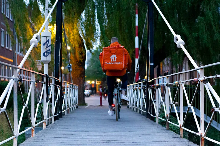 Man delivering food riding across a bridge on a bicycle