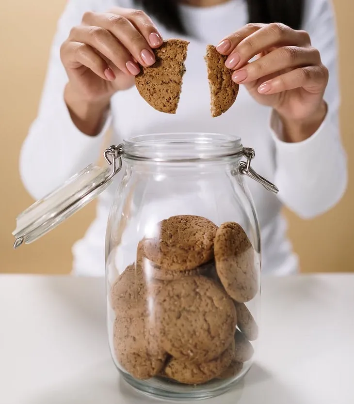 Close-up of woman taking a cookie out of a cookie jar.