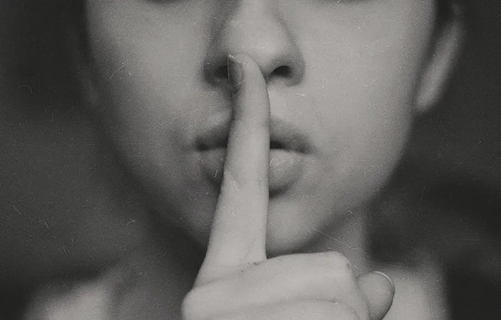 A woman’s face with her finger to her lips