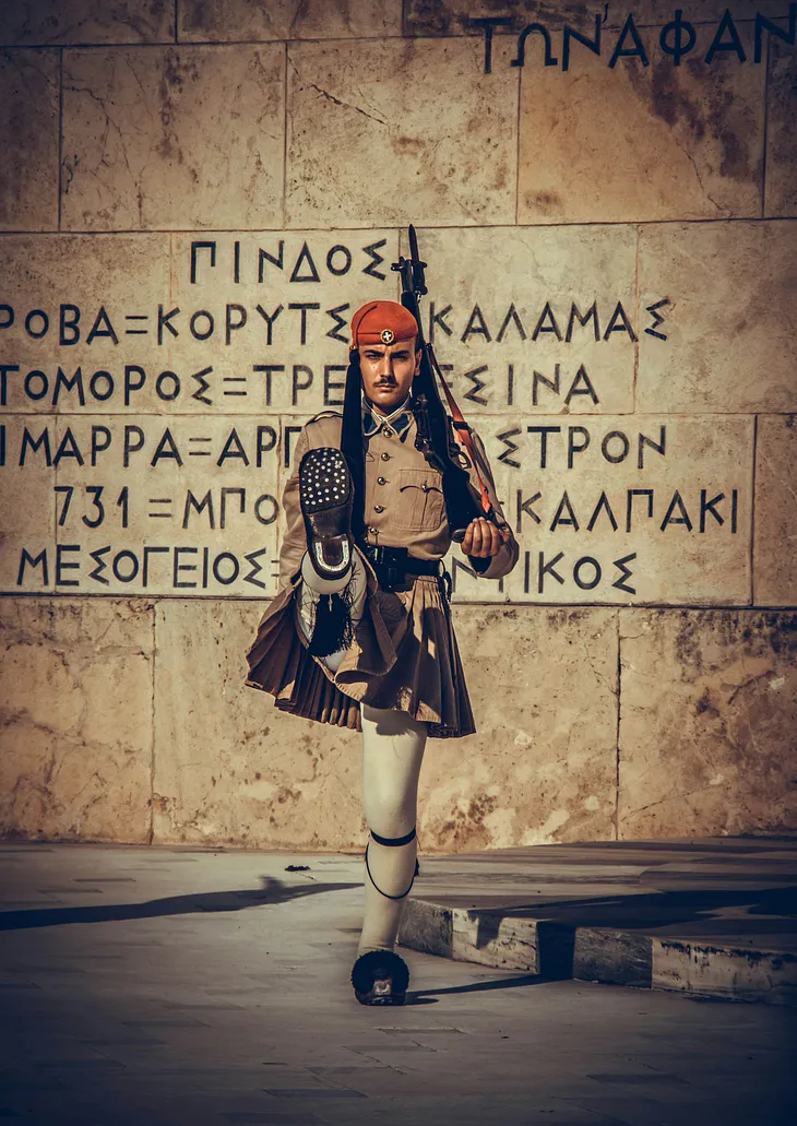 An Evzone stands guard before the Monument of the Unknown Soldier at the Greek Parliament.