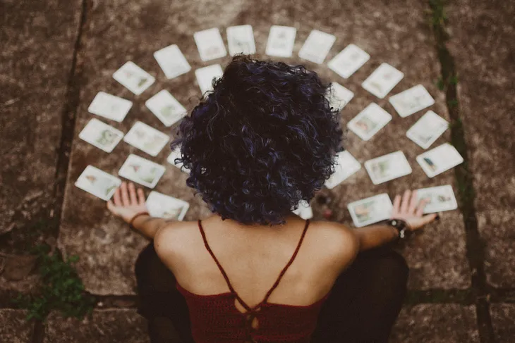 Back view of a sexy woman reading cards on a table in front of her.