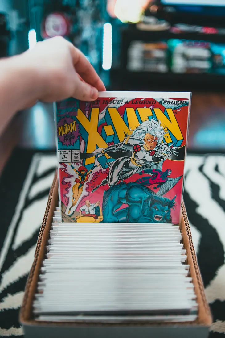 Somebody pulling an X-Men comic book from a box of comics.