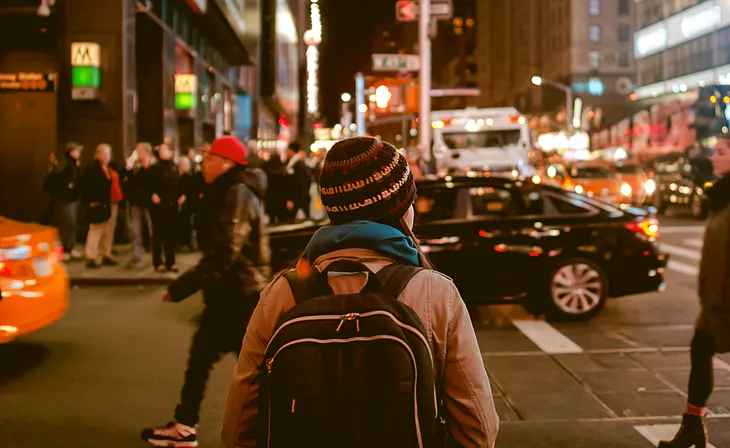 Traveller with cap and packsack in the city.