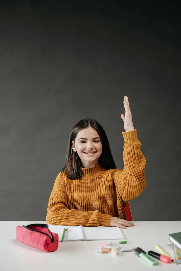 A young girl smiles at her desk in a classroom