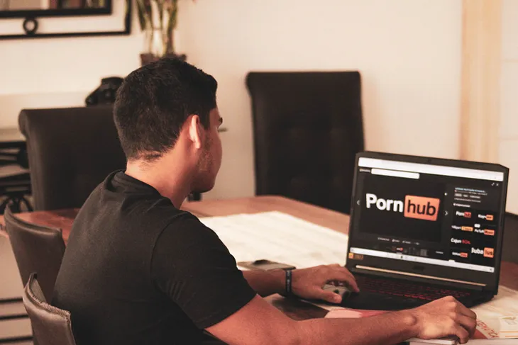 A man looks at the PornHub logo on his computer screen.