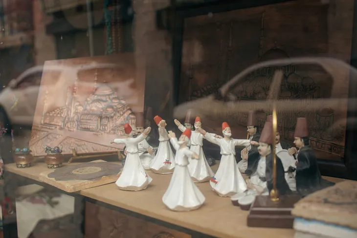 A set of Sufi dancer figurines whirl inside a shop window…