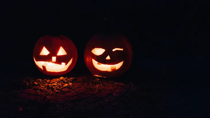 Two Jack-o-lanterns lit at night.